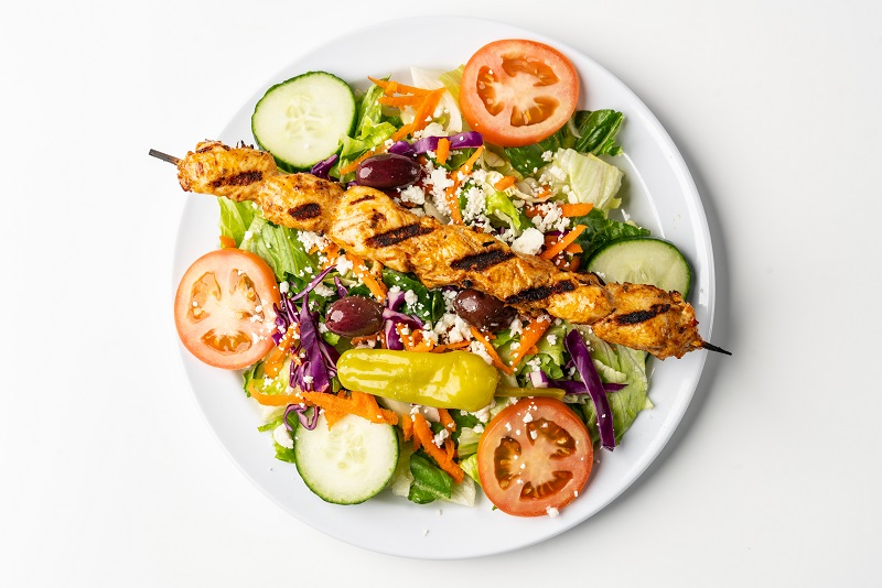 Greek salad topped with chicken kebab