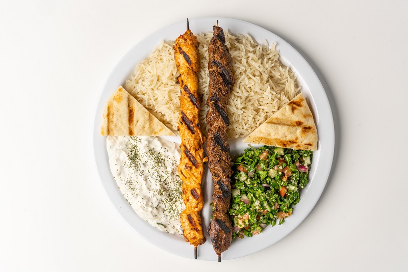Mediterranean catering platter with rice, grilled meat, salad, and pita